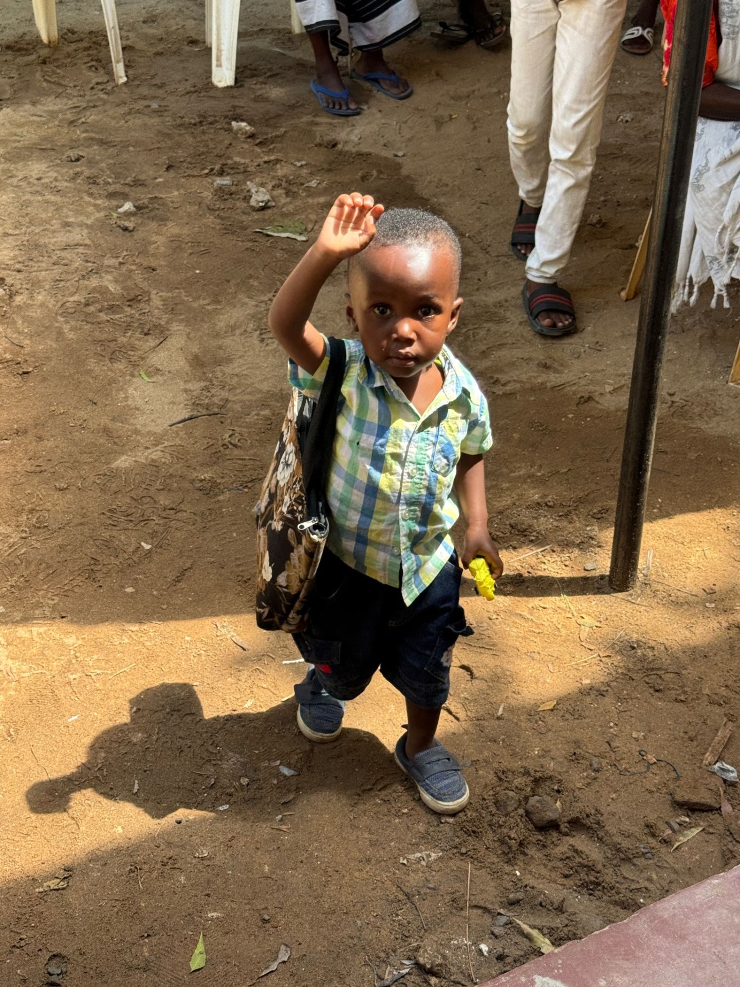 A young Kenyan child wearing a backpack and smiling, representing the children we serve